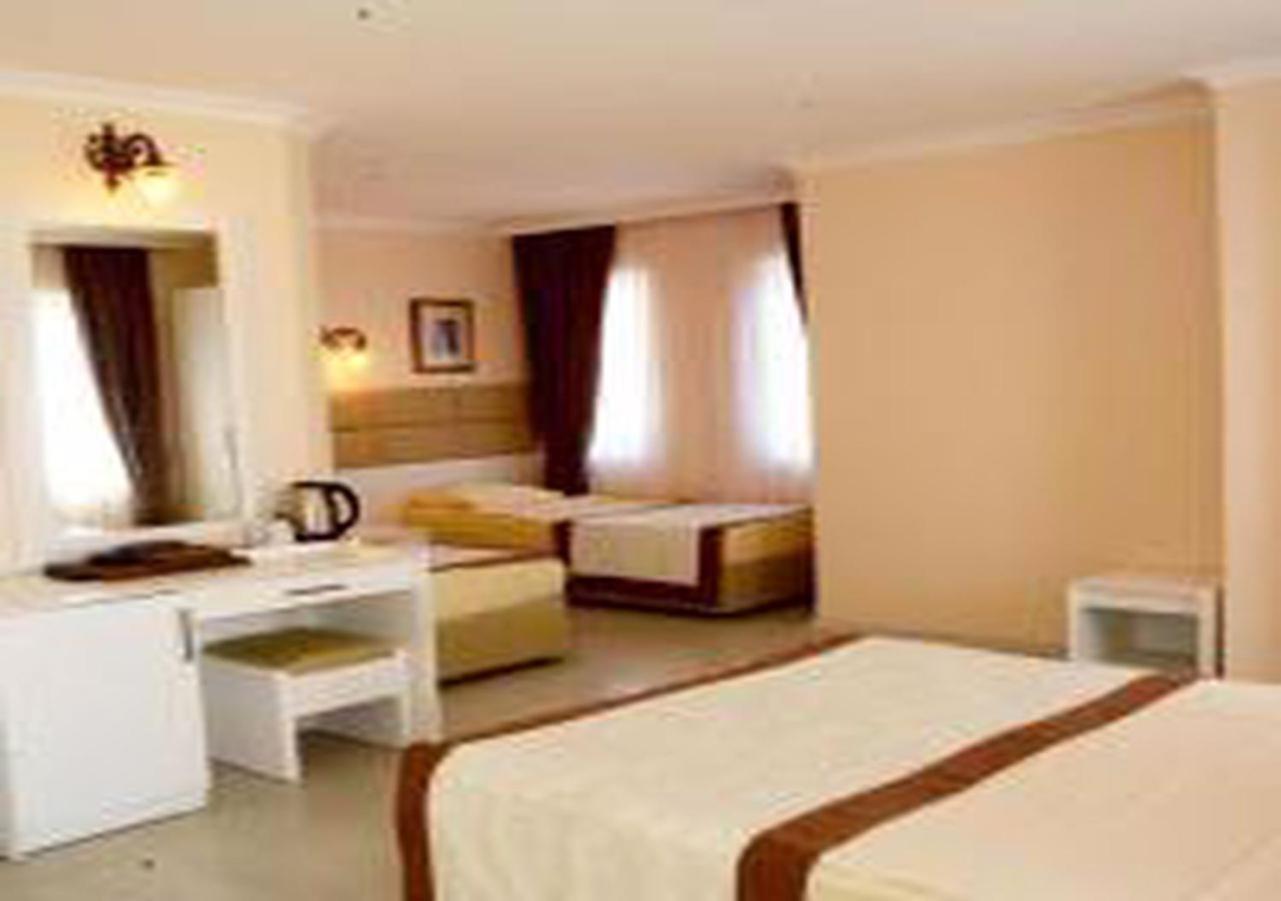 Miramor Hotel & Spa Antalia Esterno foto The photo shows a hotel room with two beds and a cozy, inviting atmosphere. One bed is larger, possibly a queen or king size, and is draped with a light-colored bedspread that has a brown accent. The room has light-colored walls and natural light str